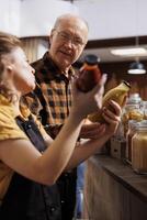 Father and daughter shopping in zero waste store looking for farm grown bulk products. Family members purchasing pantry staples from local neighborhood shop fighting against consumerism culture photo