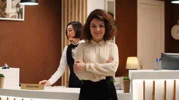Hotel manager handing folders of tourist accommodation information paperwork to cheerful receptionist. Happy smiling professional personnel working in stylish resort lounge photo