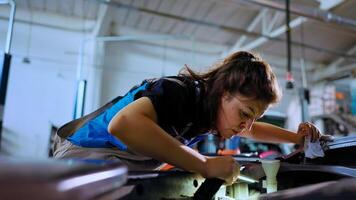 pov Disparo de meticuloso ingeniero apertura coche capucha en reparar comercio, utilizando trabajo ligero a cheque para daños y perjuicios durante rutina mantenimiento. garaje trabajador utilizando profesional herramienta a Mira dentro automóvil foto