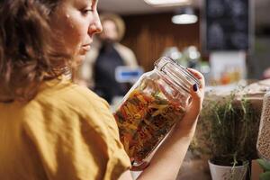 Environmentally conscious customer in zero waste bulk products shop looking for homemade pasta. Client purchasing organic non GMO food in eco friendly local neighborhood supermarket photo