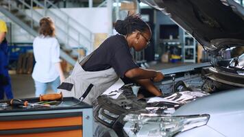 Qualified repairman in garage using torque wrench to tighten bolts inside opened up vehicle, preparing to change oil. Auto repair shop expert doing checkup on car using professional tools photo