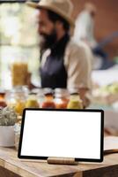 Close-up of digital tablet with a white screen display is horizontally placed on a wooden counter. Selective focus on smart device displaying isolated copyspace mockup template. photo