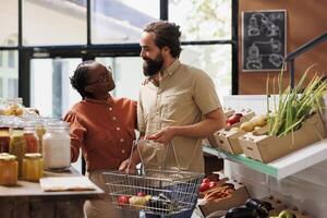 contento multicultural Pareja hojeada en sostenible eco simpático almacenar. africano americano mujer y caucásico hombre con un cesta buscando bio comida productos para un sano estilo de vida. foto