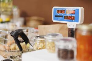 Close up shot of eco friendly checkout counter displaying weighing scale, barcode scanner, and variety of fresh sustainable products in glass containers. photo