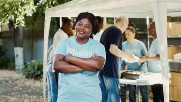 a comida conducir Caritativo evento, africano americano hembra voluntario sonrisas y posa humanitario ayuda programa Proporcionar hambre alivio y asistencia a Vagabundo y esos vivo en pobreza. foto