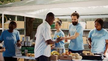 Multicultural hunger relief team distributes free meals to the hungry while also assisting and supporting the homeless. Volunteers distributing hot meals in an effort to reduce hunger and poverty. photo