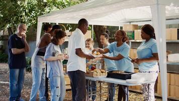 People from many backgrounds assemble outside to distribute non-perishable donations and help the poor and homeless. Multiracial volunteers provide needy individuals with free, freshly prepared meals. photo