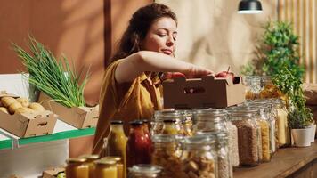 Vegan woman in specialty zero waste supermarket counting apples, adding them to shopping basket. Client in local neighborhood grocery shop picking freshly harvested fruits photo