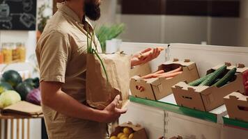 vegano hombre en cero residuos supermercado utilizando no contaminante papel bolso mientras compras para natural vegetales. cliente en bajo carbón huella local tienda de comestibles tienda con No soltero utilizar plástica política foto