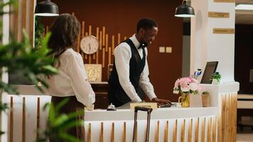 Woman ringing service bell at reception, calling for front desk staff to help with room reservation check in. Diverse employees at hotel ensuring pleasant stay for retired person. Handheld shot. photo