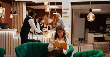 Receptionist gives access key card to hotel guest, finishing with check in process and heading to room with bellhop. Concierge employees assisting senior man to ensure relaxing trip. photo