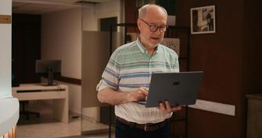 Older person searching for places to visit on laptop, using wireless connection at hotel before registering procedure. Retired man travelling abroad on vacation, browsing online information. photo