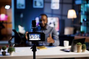 Professional camera used to record tech tutorial on how to repair damaged electronics. Technology guru in blurry background using video production gear to produce content for audience photo