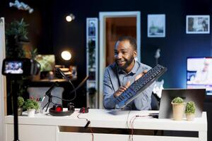 Cheerful media star being sponsored by partnering brand to do gaming keyboard unboxing content. Tech guru does influencer marketing, doing product placement of computer peripherals photo