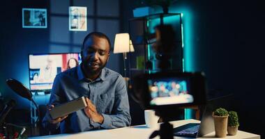 africano americano en línea estrella haciendo tecnología revisión de Bluetooth portátil altavoz para en línea transmisión canal. bipoc hombre de influencia Película (s música jugando dispositivo desembalaje para su audiencia foto