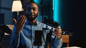 Tech content creator filming technology review of newly released gaming VR glasses for audience in home studio. BIPOC influencer showing virtual reality headset to subscribers photo