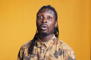 African american confused man pondering decision, focused on introspection thoughts in studio over yellow background. Thoughtful unsure young adult questioning business solution, puzzled expression photo