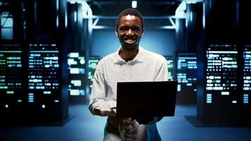 Computer scientist walking between data storage devices in computing server room, ensuring proper operations conditions. Serviceman monitoring high tech facility infrastructure energy consumption photo