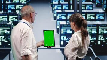 Skillful supervisor looking around high tech data center, using mockup laptop to crosscheck disaster recovery plan and assess servers racks in need of replacement, preventing troubles photo