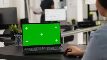 analista comentarios pantalla verde monitor en computadora portátil, trabajando en pequeño negocio operaciones y tareas. mujer de negocios mirando a ordenador personal pantalla con blanco chromakey copyspace diseño en agencia oficina. foto