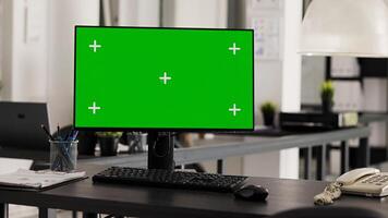 Empty office desk with pc running greenscreen on display, showing isolated chromakey template in coworking space. Workstation in open floor plan with monitor and copyspace layout. photo