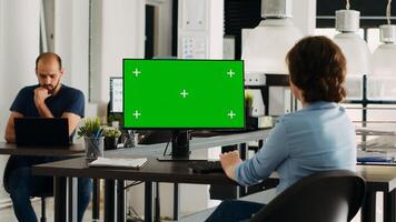 Businesswoman looking at greenscreen display to work on agency tasks, employee analyzing isolated chromakey template at desktop. Person working with copyspace, problem solving. photo