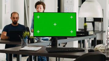 Greenscreen template on pc in office, modern computer showing isolated chromakey display in coworking space with employed agency people. Blank mockup screen on monitor, empty desk. photo