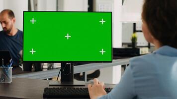 gerente trabajando con aislado pantalla verde en computadora a puesto de trabajo, mirando a chromakey monitor con Bosquejo modelo en escritorio. mujer de negocios utilizando ordenador personal en trabajo colaborativo espacio. foto