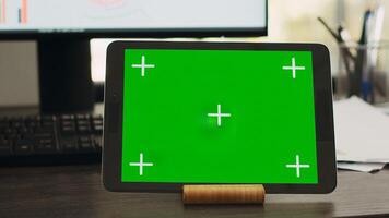 Empty desk with greenscreen on tablet in business coworking space, isolated copyspace layout on modern gadget display. Workstation with device showing chromakey mockup screen. photo