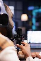 Black guy in close up shot is seen wearing wireless headphones and using modern microphone to conduct an online talk show. African male person using audio equipment, recording a podcast episode. photo