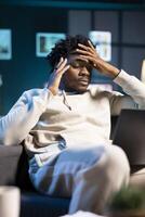 Anxious overworked man struggling to concentrate while working from home, hurting from severe headache. Tired teleworker exhausted after sleepless night, struggling to pay attention on tasks photo
