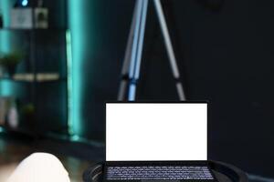 Close up shot of mockup laptop used by man relaxing in apartment by watching TV series. Person at home looking at television shows on isolated screen notebook placed on coffee table photo