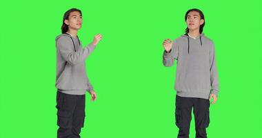 Young adult checking hologram icon in studio with greenscreen backdrop, looking at modern holographic image and focusing on work. Asian casual guy using artificial intelligence. photo