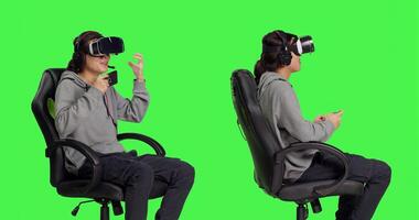 Asian guy plays mobile game with vr headset in studio, enjoying online rpg competition using virtual reality technology on smartphone. Young adult gamer having fun with friends. photo