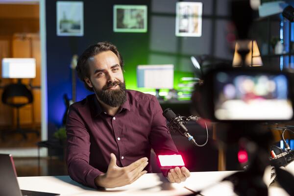 Cheerful influencer happily endorsing mini led lights from sponsor during live broadcast, recording with professional camera. Smiling content creator advertising RGB lighting device sponsorship