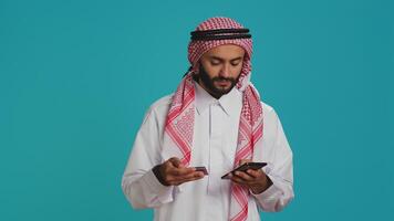 Arab person adding card numbers on website, doing online shopping spree on mall store retail app. Person paying for things on internet page, wearing traditional islamic attire with scarf. photo