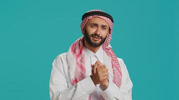 Hopeful muslim guy begging and asking for something, holding hands in a prayer and having faith. Middle eastern adult being desperate and seeking help, saying please in studio. photo