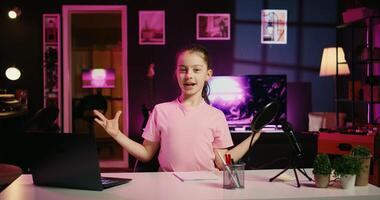 Happy child and her loving mom recording family vlog intro on online platforms. Young smiling daughter and parent warmly welcoming dedicated gen Z fans, filming in home studio with pink neon lighting photo