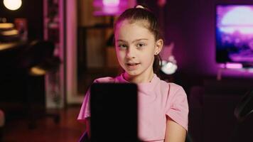 Focus shot on smartphone attached to tripod used for recording family vlog with kid in blurry background talking about school with children audience, filming content for social media, close up photo
