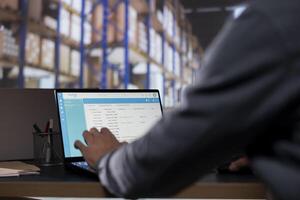 Inventory supervisor verifying checklist for order shipment in depot, creating invoices for cargo stock. Storage room employee managing dispatch notes to ensure easy delivery and goods distribution. photo