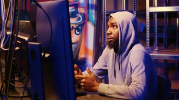 Zoom in shot on african american hooded hacker targeting vulnerable unpatched connections, seeking to compromise digital devices and steal valuable sensitive data from them photo