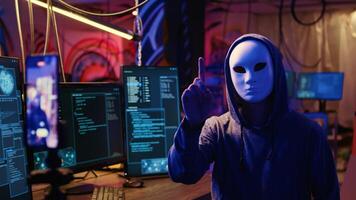 Masked hackers filming video threatening to not stop coordinating DDoS attack on website and send large amounts of traffic from multiple sources to overwhelm it unless their demands are not met photo