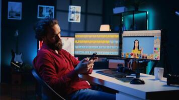 Photographer taking break from using photo editing software on PC display, texting friends to relax. Freelancer stops using photographs retouching program to spend time on mobile phone