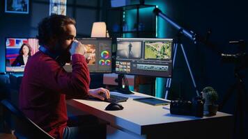 Video editor polishing raw footage, applying modern editing techniques in order to enhance clarity, sharpness and brightness. Videographer adjusting clips while enjoying cup of coffee in office photo