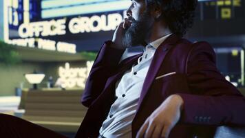 Financial advisor on phone call with accountant at night, sitting on a bench in front of skyscraper office building in the city center. Confident investor trying to obtain new funds from partners. photo