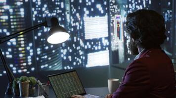 Inspector evaluating legal accounting records and operations for efficiency, working at night in luxury headquarters to smooth out funding concerns for the president. Broker sells in stock market. photo