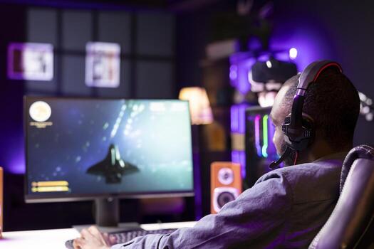 Man shoots asteroids in spaceship flying singleplayer game on gaming PC with overlay HUD showing health, fuel bars. Gamer navigating universe in simulation game, chatting with friends using headphones photo