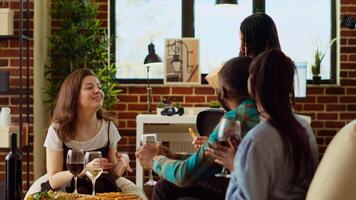 Multiracial mates invited to birthday party offering presents to asian woman. Guests surprising their friend with neatly packaged present in her apartment, drinking wine and socializing photo