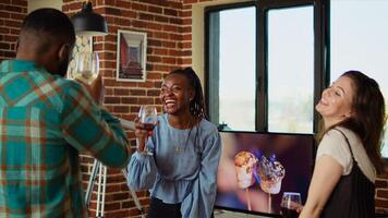 Young adults of various nationalities dancing at apartment party while drinking alcoholic beverages. Friends hanging around, having good time together while enjoying electronic songs in living room photo