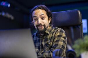 Creative writer, smiling and typing on laptop, passionately engaged in his work, combining technology and creativity. Cheerful man looking at device screen, checking emails and reviewing information. photo